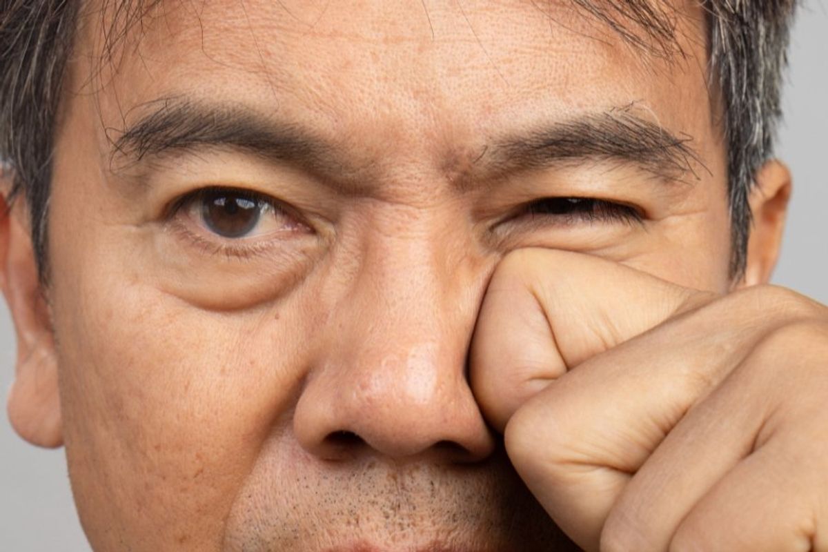 man pushing on his eyelid with finger