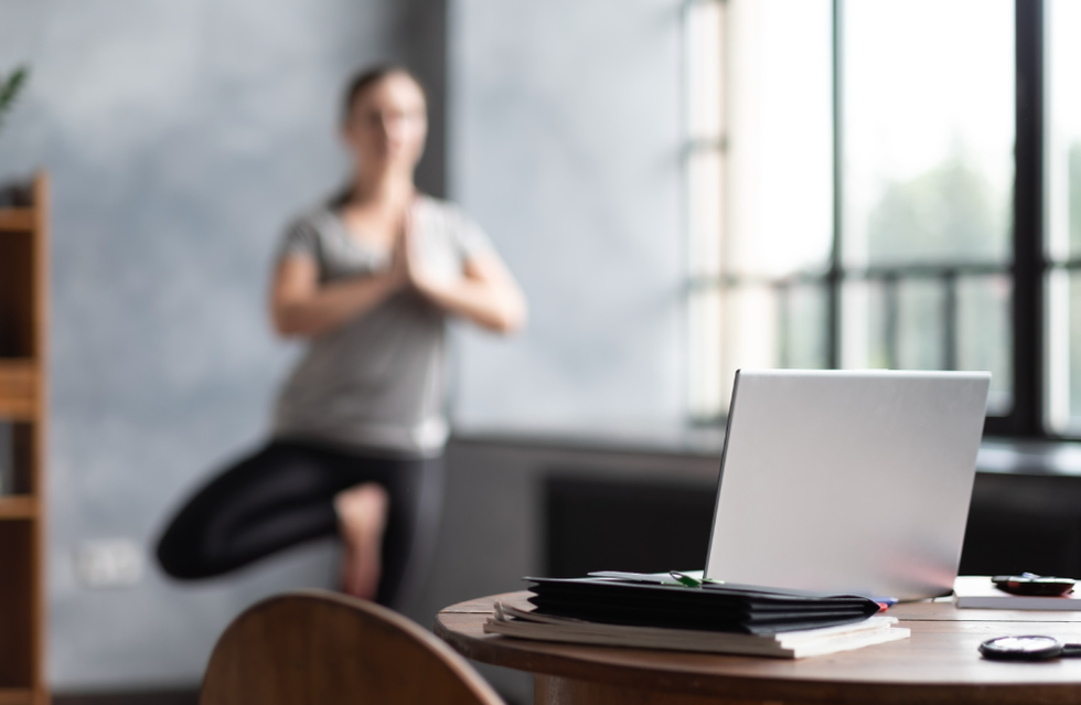 Woman doing yoga in front of her laptop