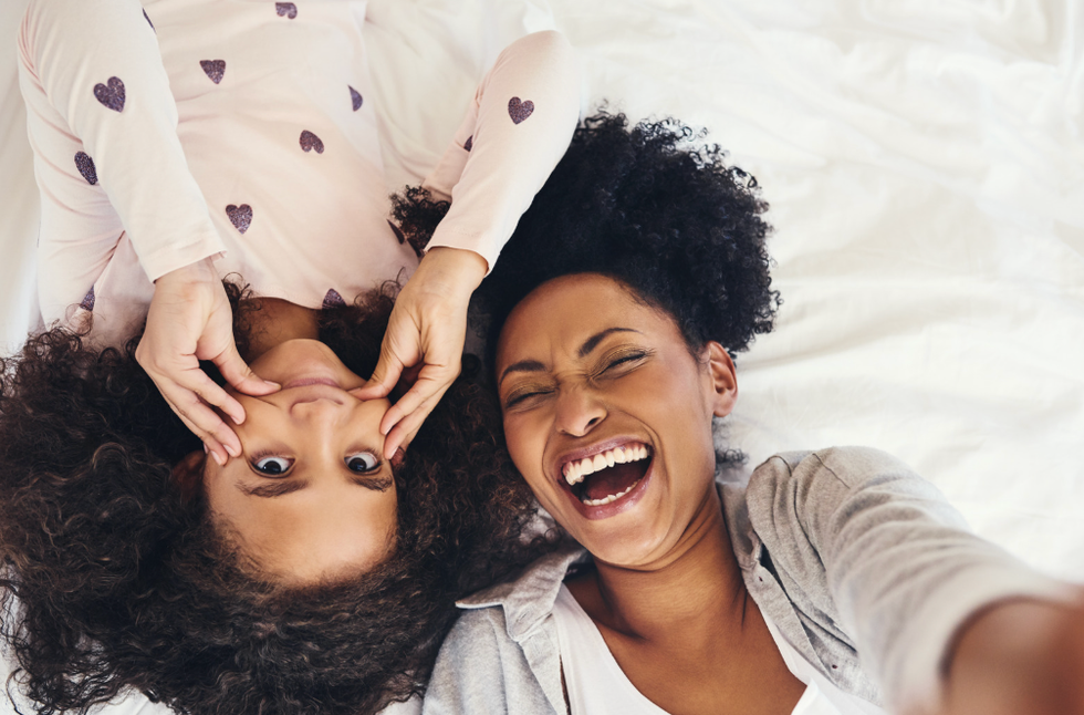A woman laughs at her daughter making a goofy face for a selfie