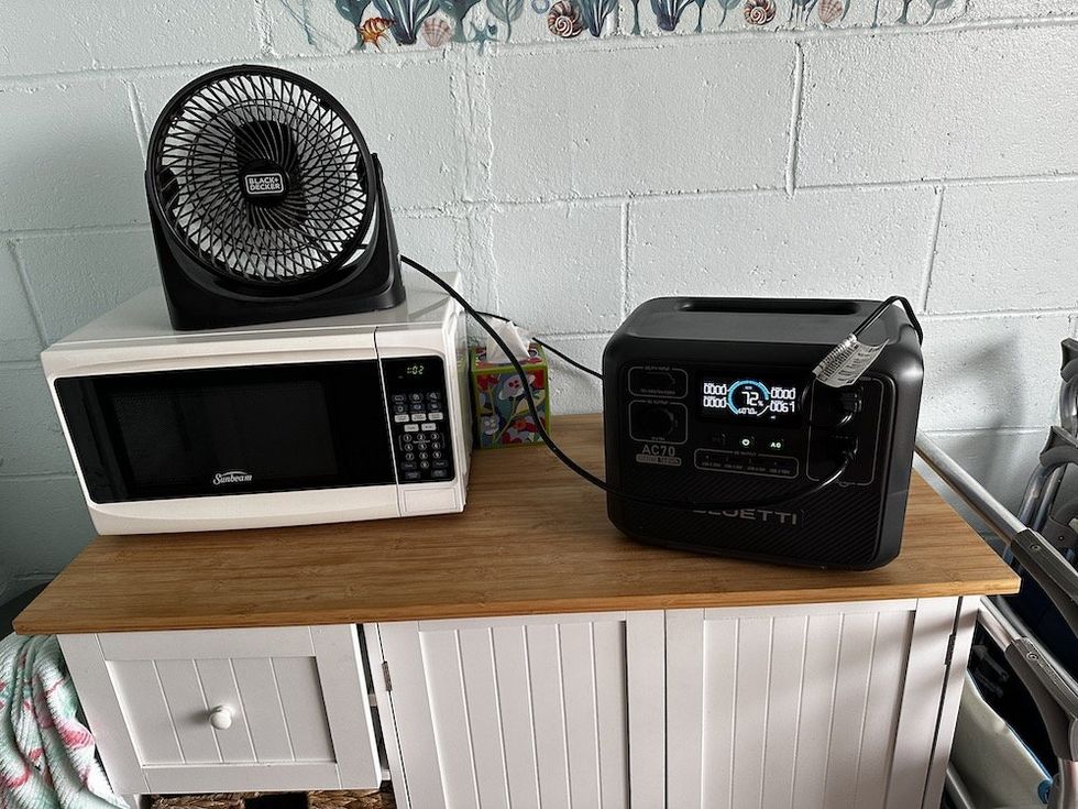 a photo of Bluetti AC70 powering a fan and microwave in a cabana