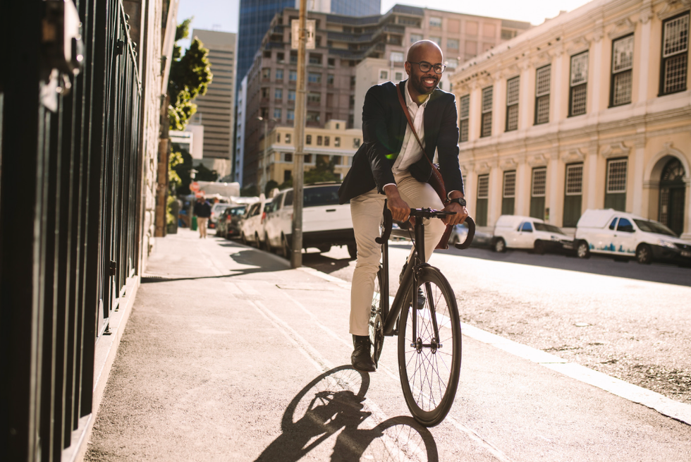 A man in formal clothes riding a bike on the sidewalk