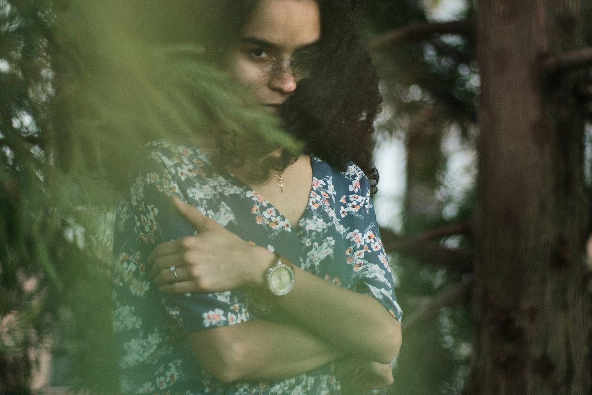 woman in blue and white floral dress standing beside green tree during daytime