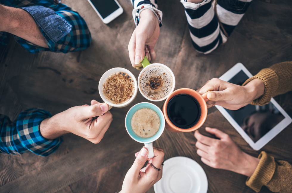 Hands hold coffee mugs, cheering