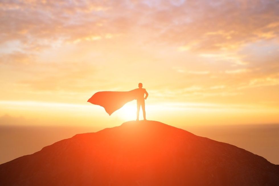 caped hero standing on a mountain