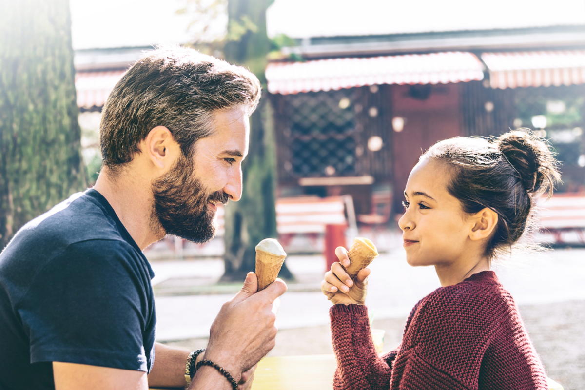 Father and daughter having ice cream outside.