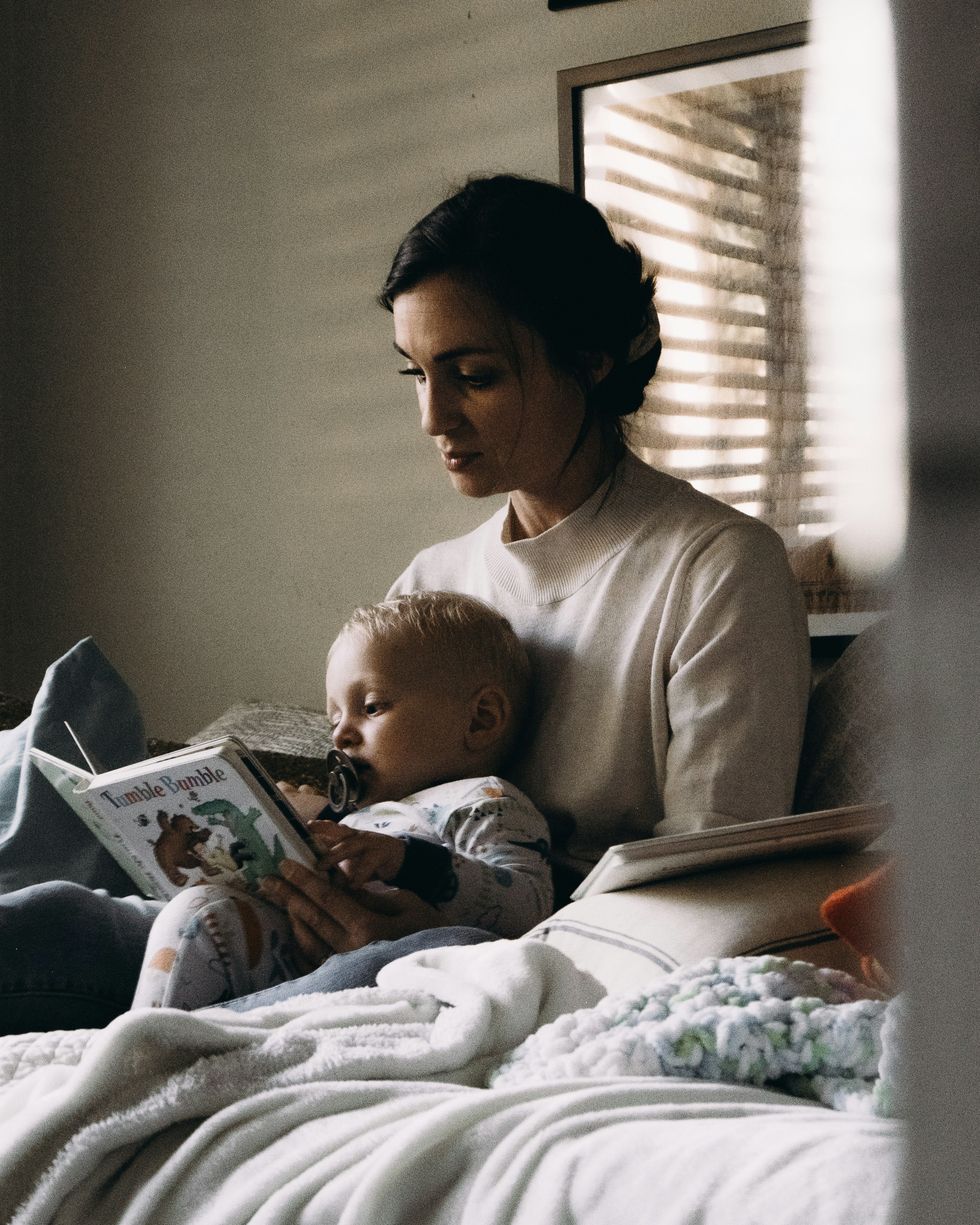 mom in white long sleeve shirt reading to baby in white onesie