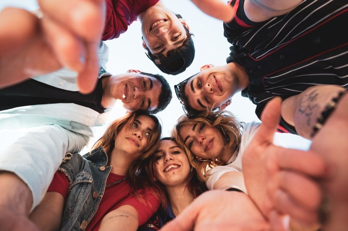young adults huddled together staring down at a camera
