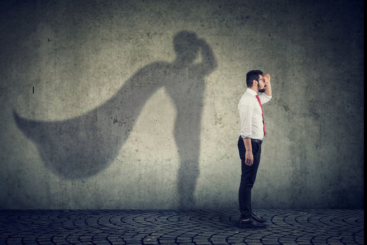 man standing with a caped hero shadow behind him
