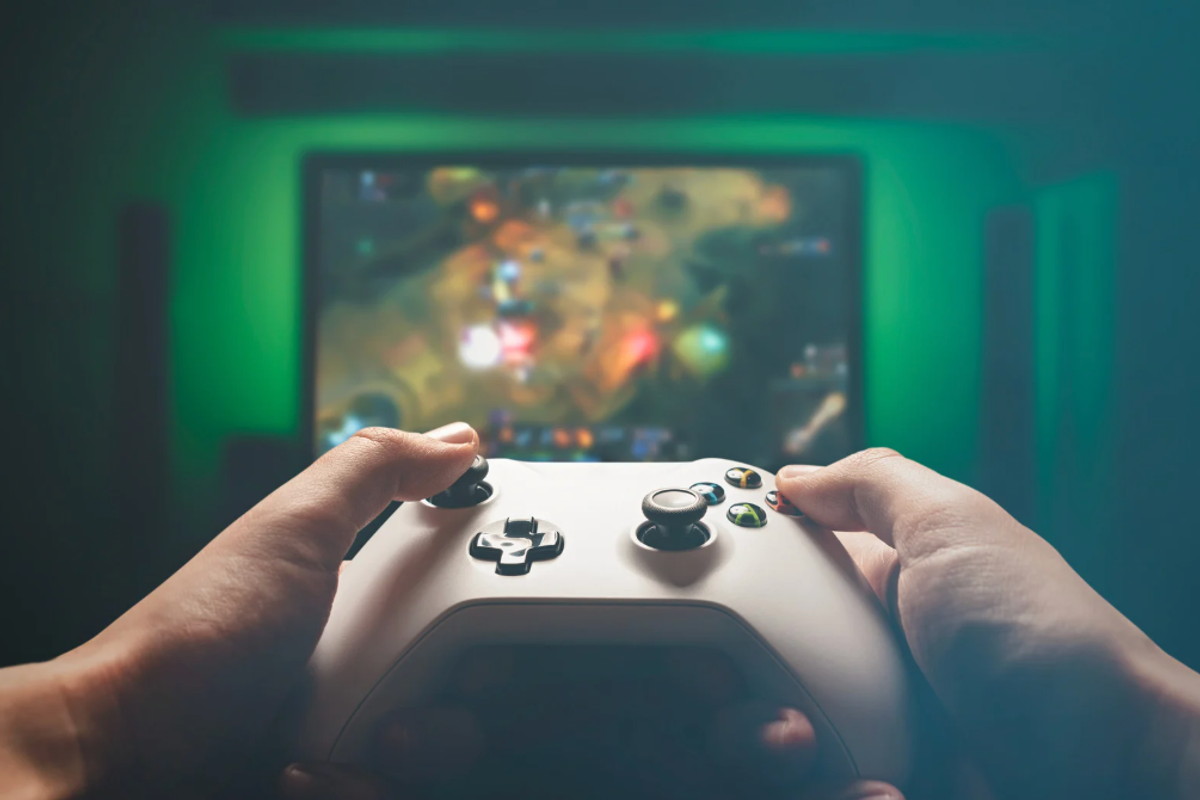 Hands on a video game controller in front of a TV