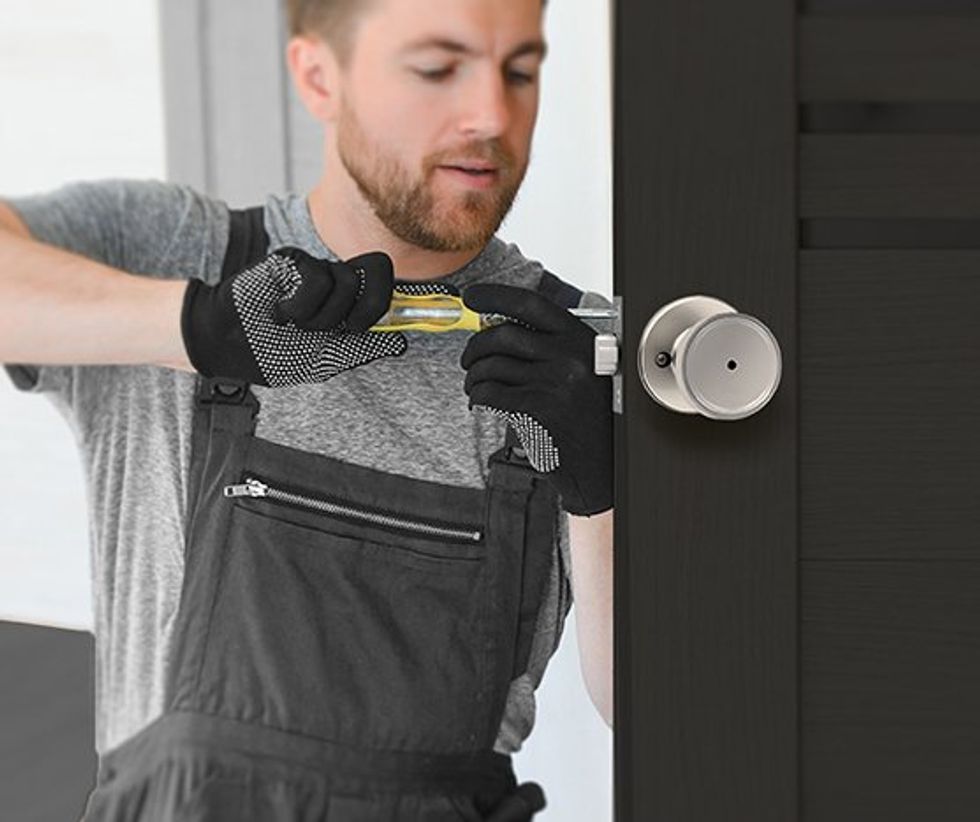 Foto seorang pria yang memasang kenop pintu Kwikset Maven di pintu