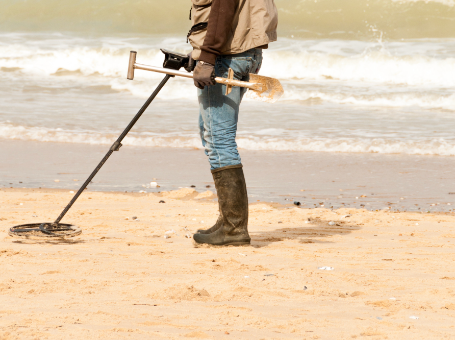 Person using a metal detector on the bach