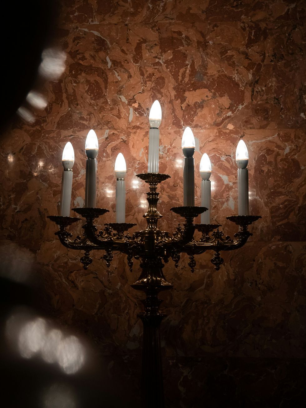 A chandelier in a room with a marble wall