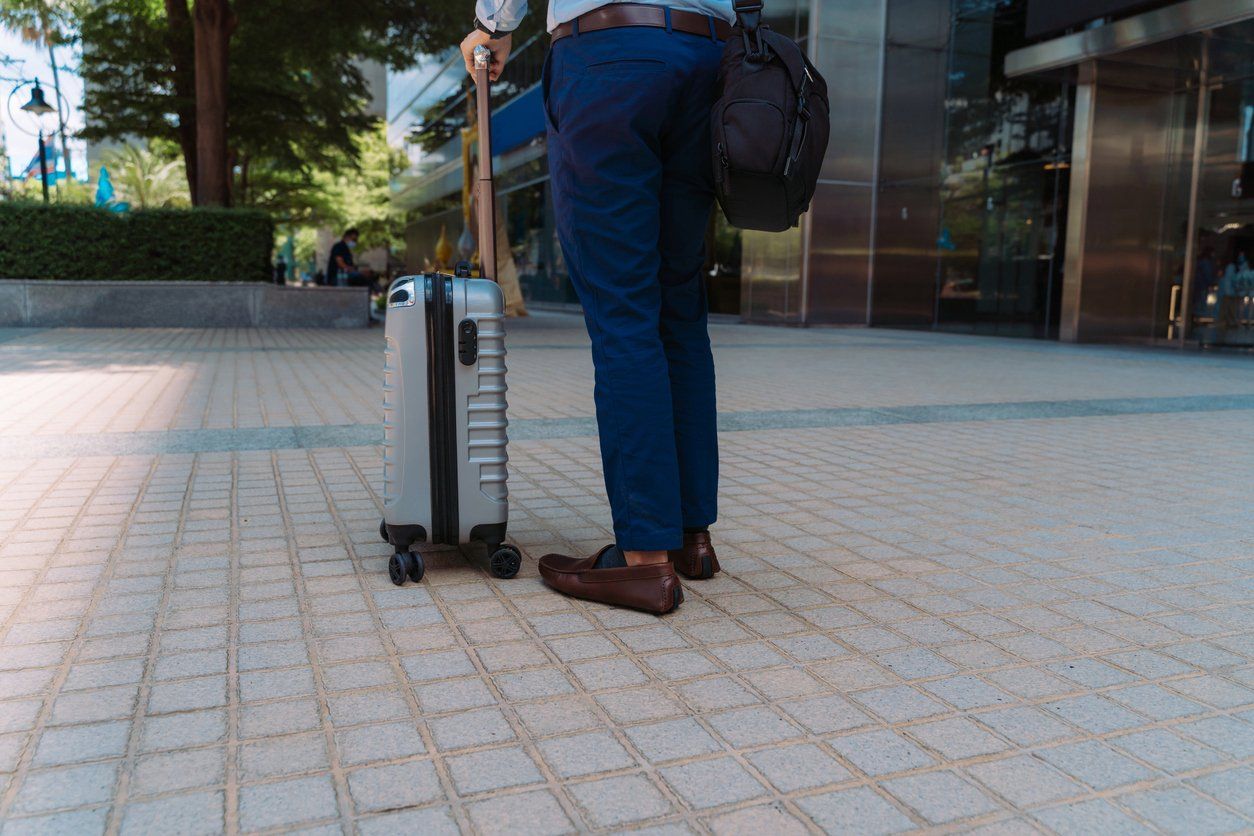 Businessman with wheeled suitcase on business trip stock photo.