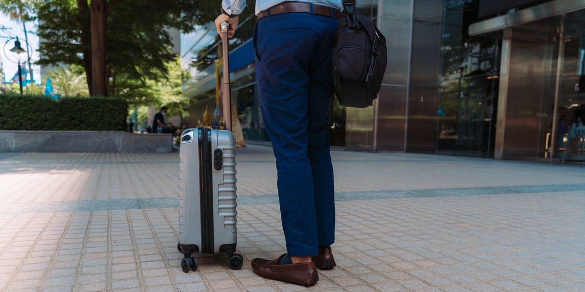 Businessman with wheeled suitcase on business trip stock photo.