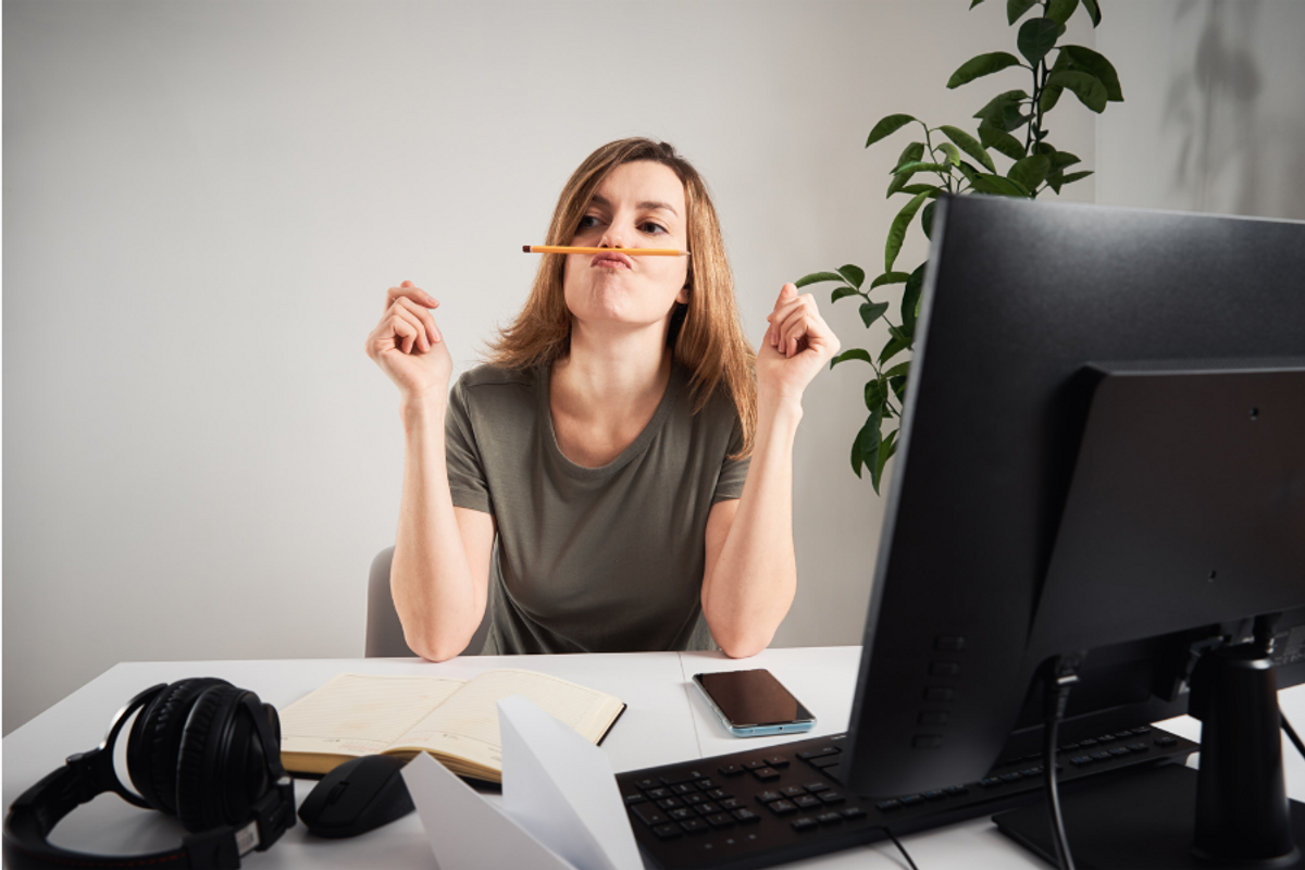 A bored-looking office worker balances a pencil on their lip