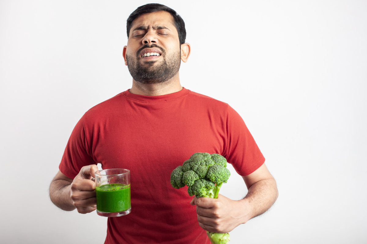 Man with broccoli and green smoothie and he's not happy about it.