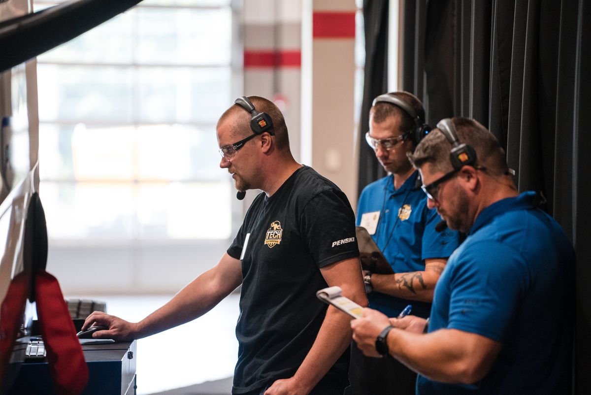 Technicians participating in a hands-on skills challenge at the 2024 Penske National Tech Showdown, showcasing precision and expertise in vehicle maintenance.