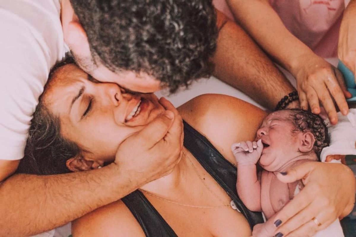 family post childbirth; mom holds baby while dad holds mom