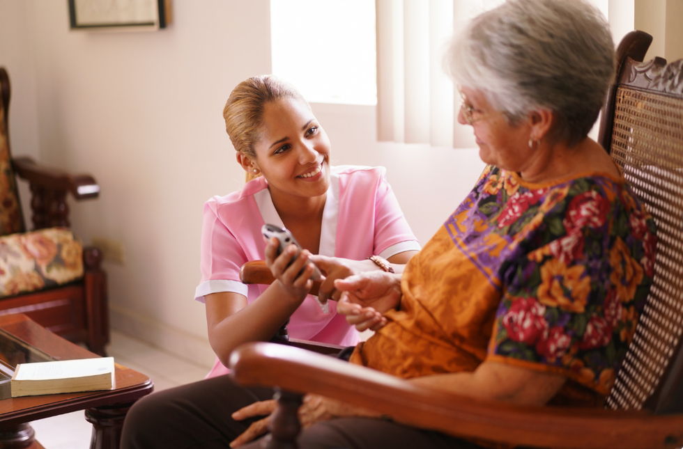 hospice nurse shows elderly woman in chair something on her phone