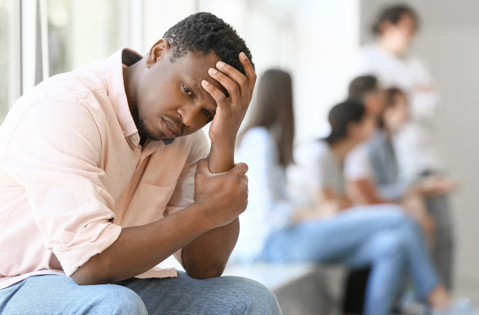 Man feeling lonely as a small crowd is in the background