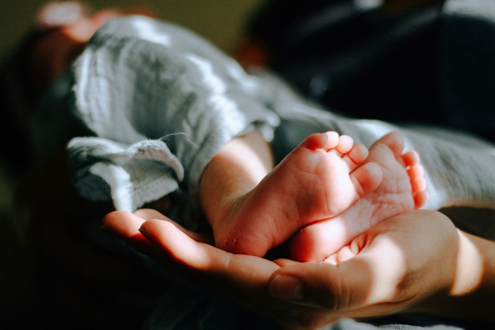 person's hand holding baby feet