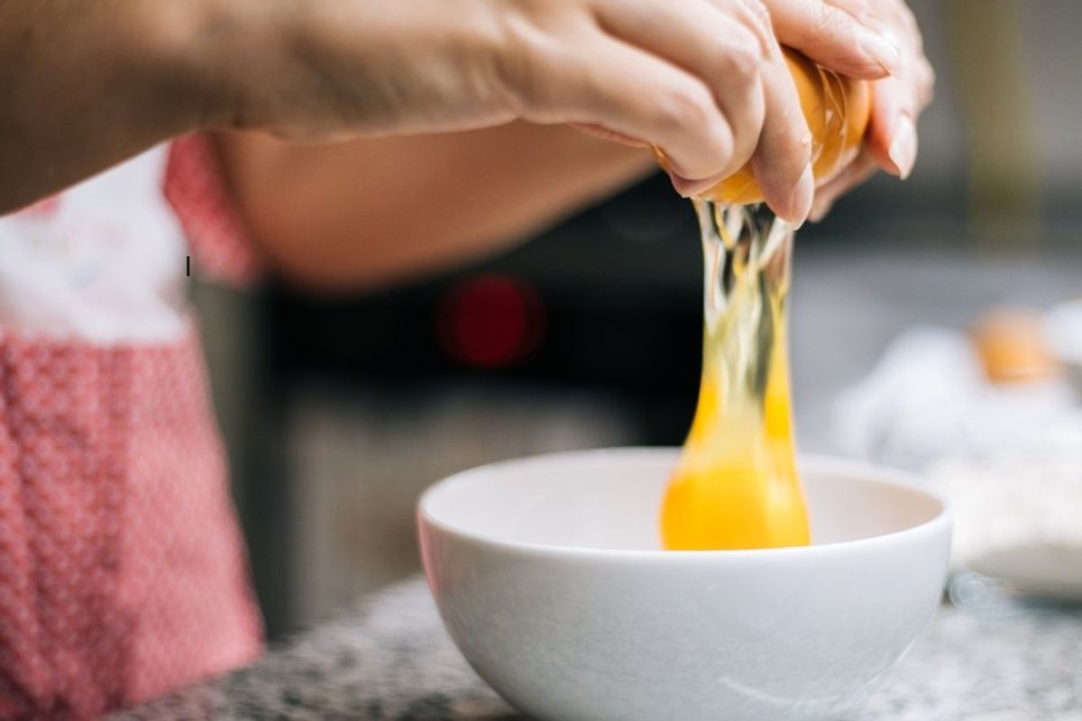 someone cracking an egg into a bowl