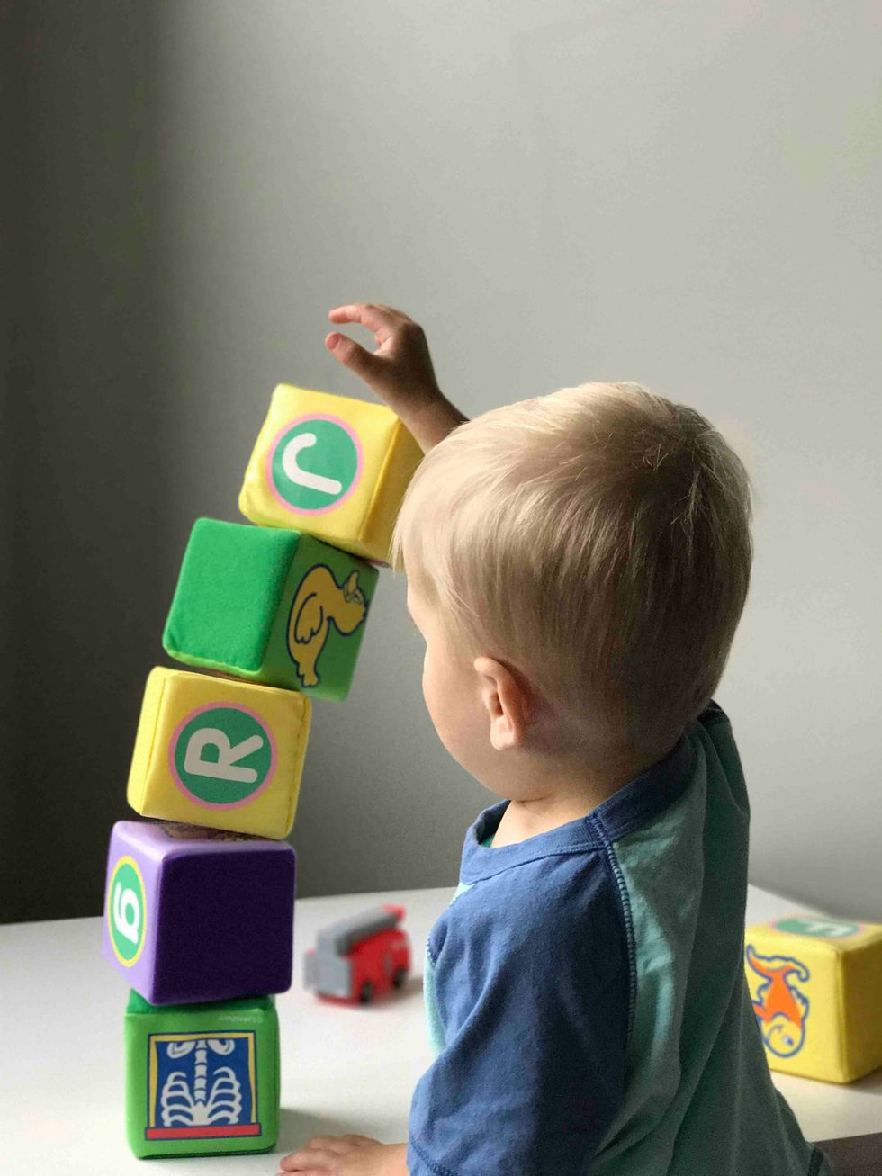 boy playing with  blocks on white wooden table