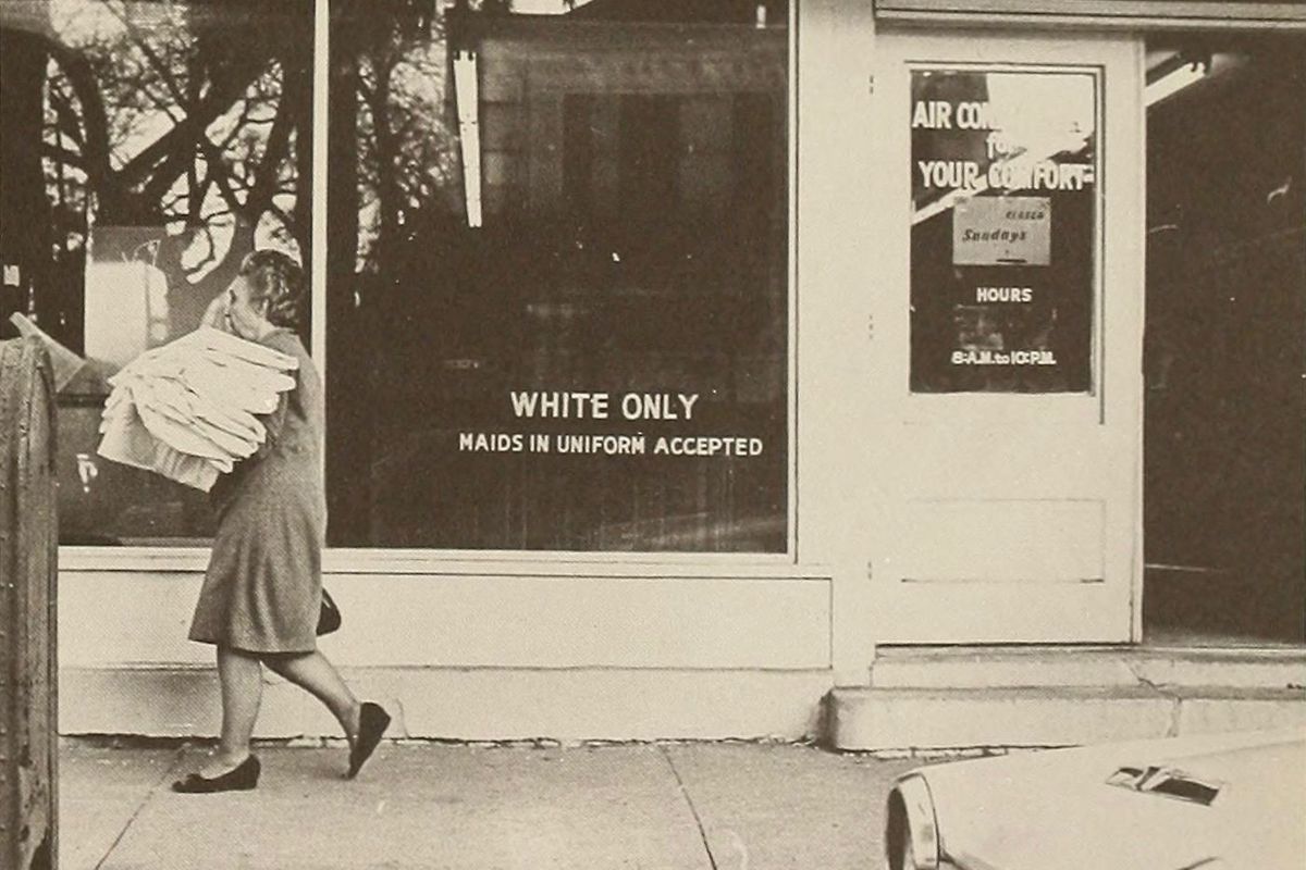 black and white photo of a storefront that reads "WHITE ONLY. Maids in uniform accepted."