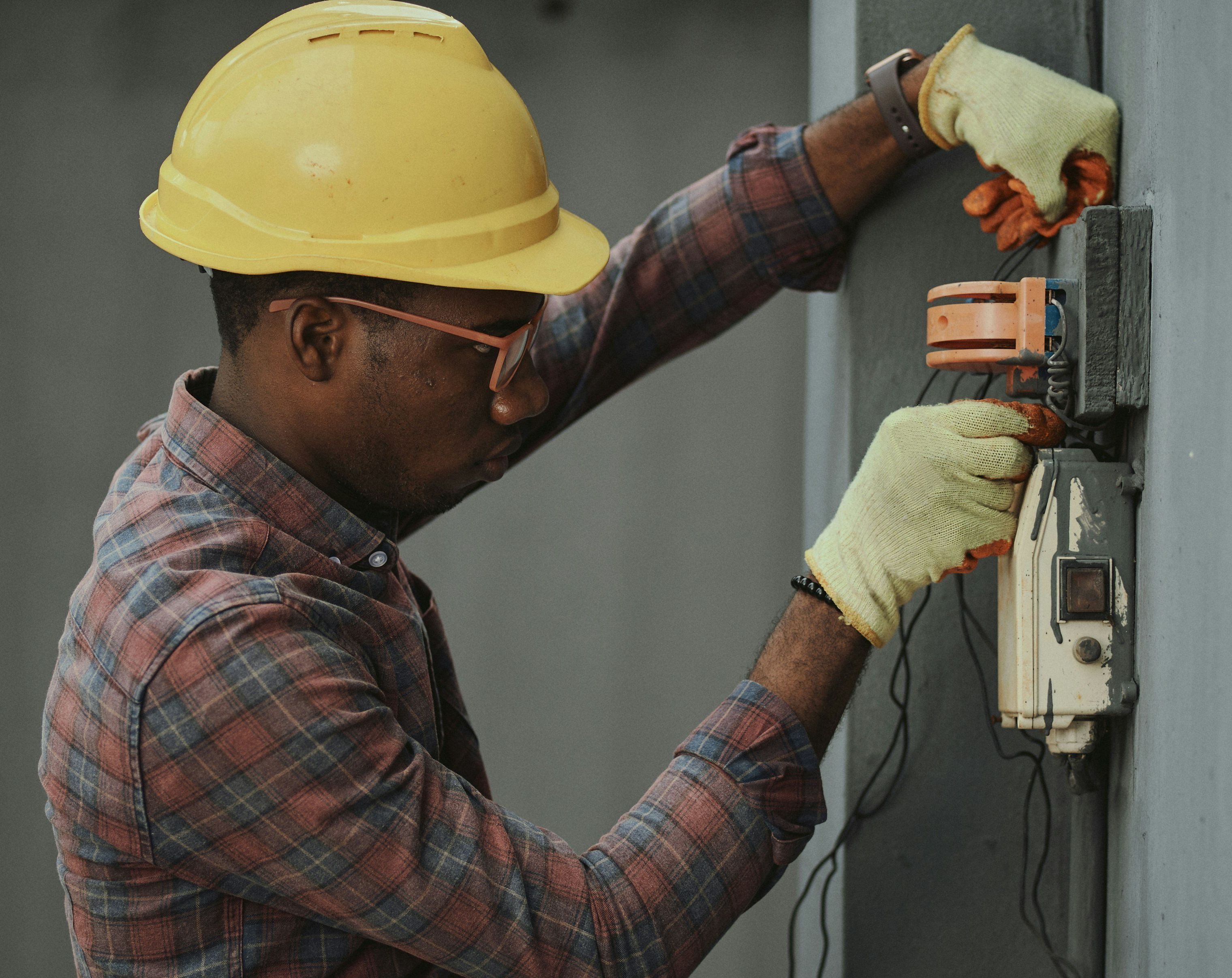 A man in a hard hat inspects an electrical box