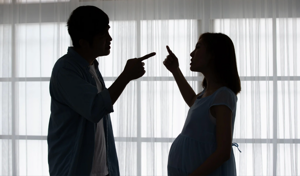 A pregnant woman and a man point fingers at each other