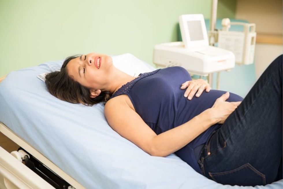 pregnant woman holding her stomach in pain 