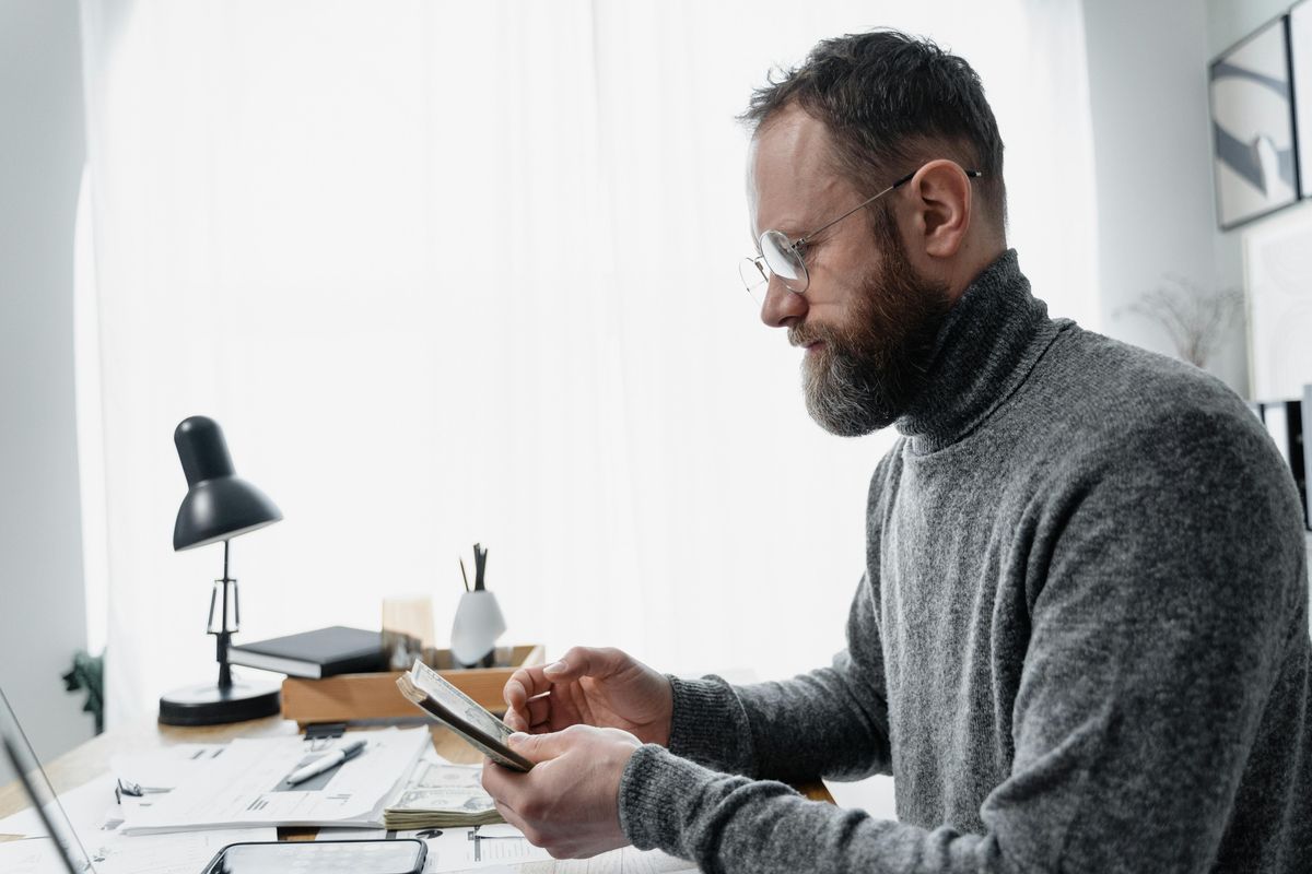 A photo of a man working at a desk on his smartphone