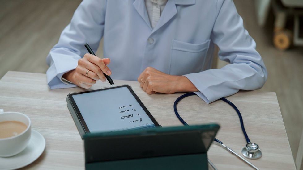 Female Doctor Talking to Patient through Video Call to Follow up on His Conditions. stock photo