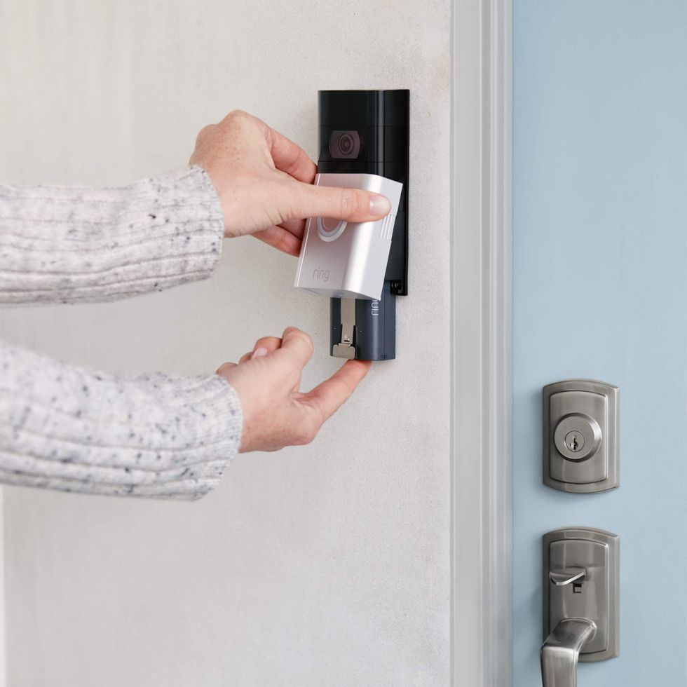 a photo of a woman placing a battery inside Ring doorbell