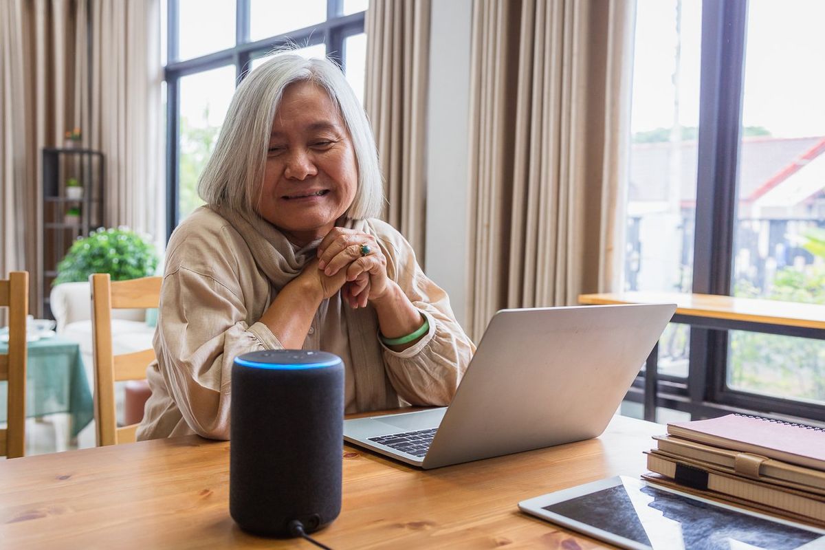 Asian senior women working with laptop computer and using smart speakers while setting in living room at home stock photo
