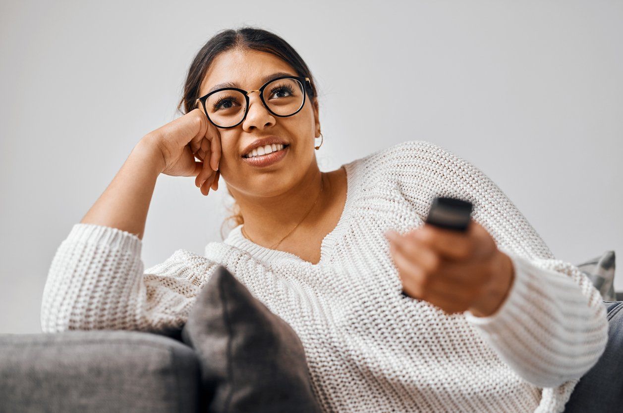 Shot of a young woman watching tv on the sofa at home stock photo