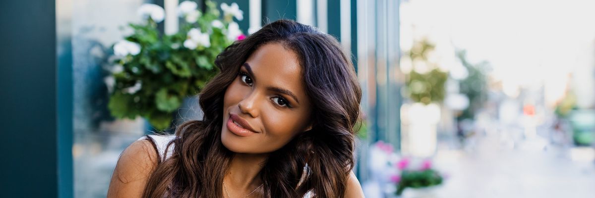 Beautiful portrait of an American girl with long curly hair sitting on a flyer in a cafe. woman smiling outdoors