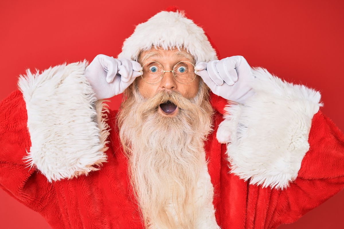 Surprised Santa with glasses, holding his frames, on a red background.