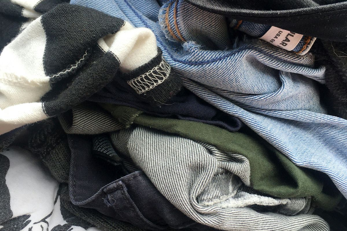 Pile of assorted clothes including denim, black, and striped fabrics.