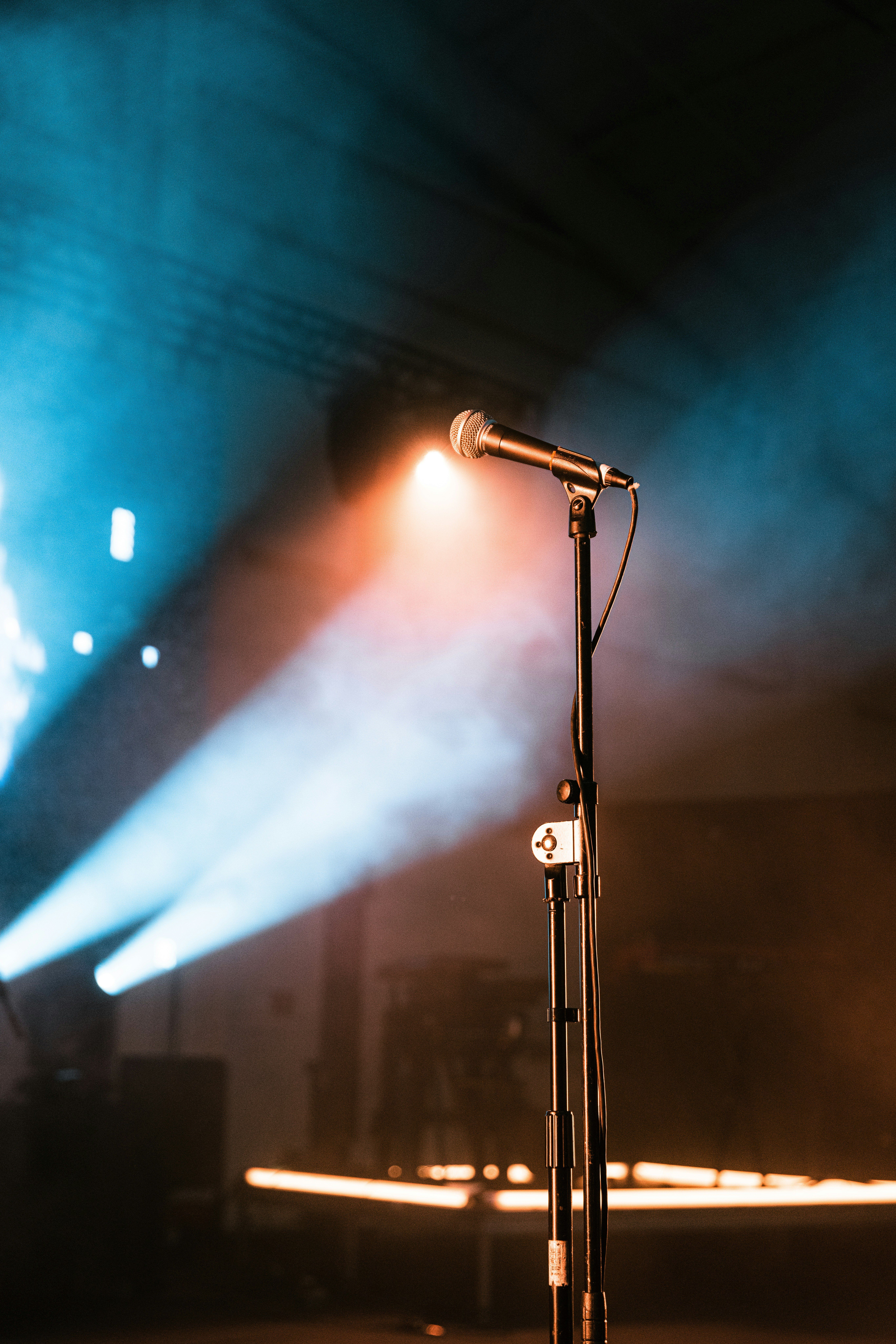 Microphone on stage with colorful spotlights and smoke.