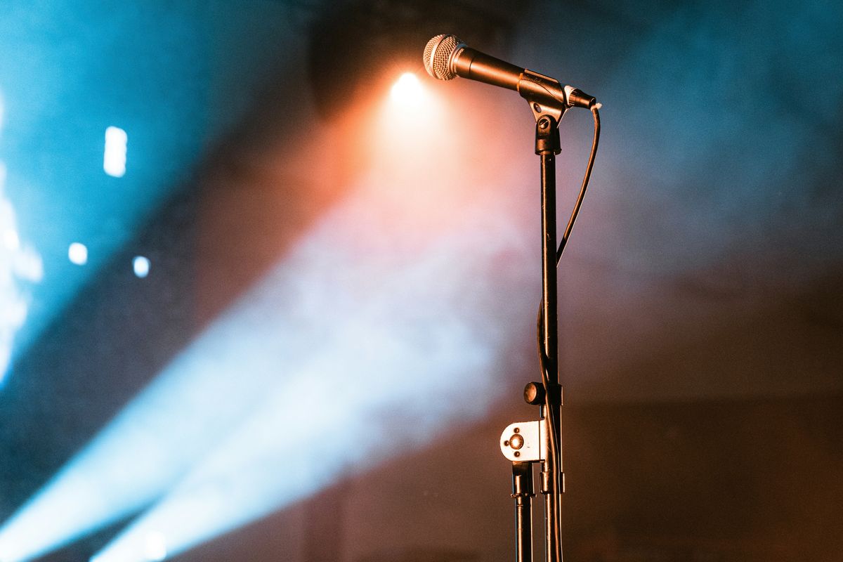Microphone on stage with colorful spotlights and smoke.