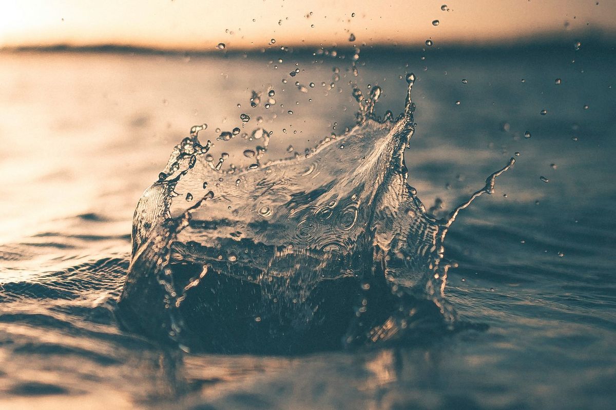 Water splash at sunset with droplets suspended in midair.