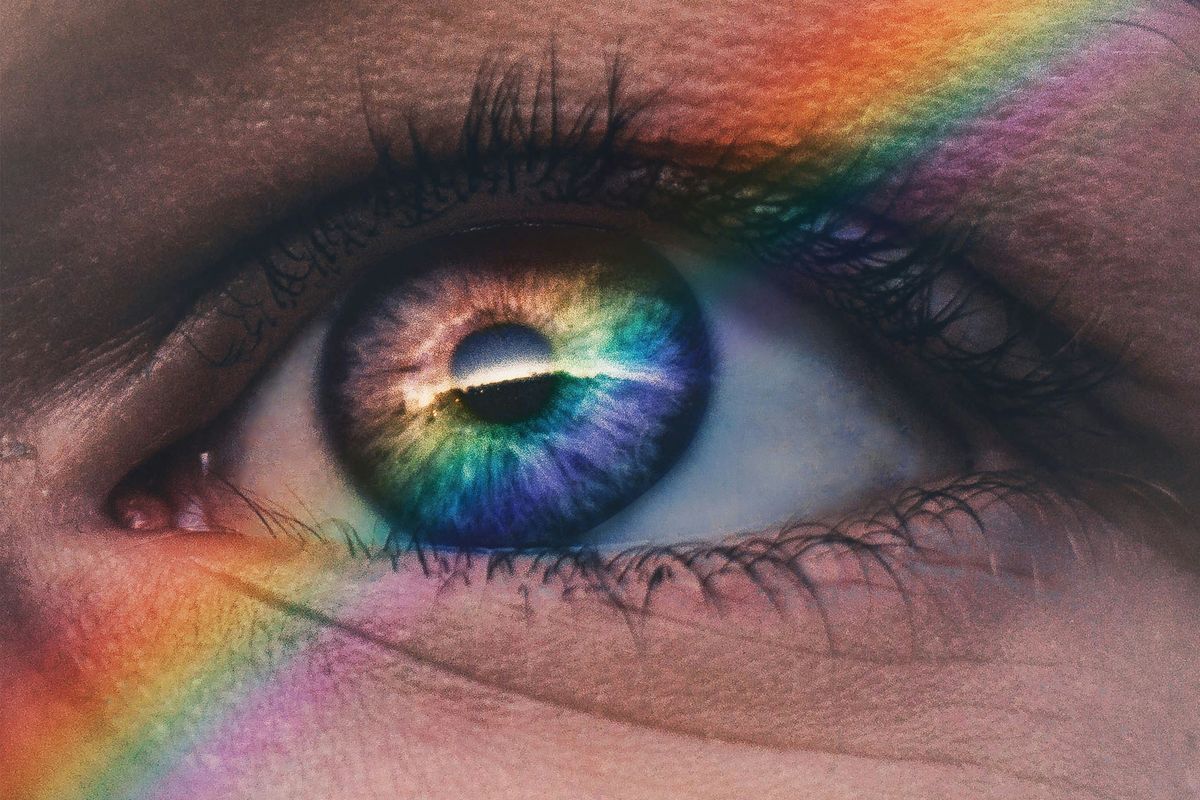 Close-up of an eye with iridescent colors and a rainbow reflection.