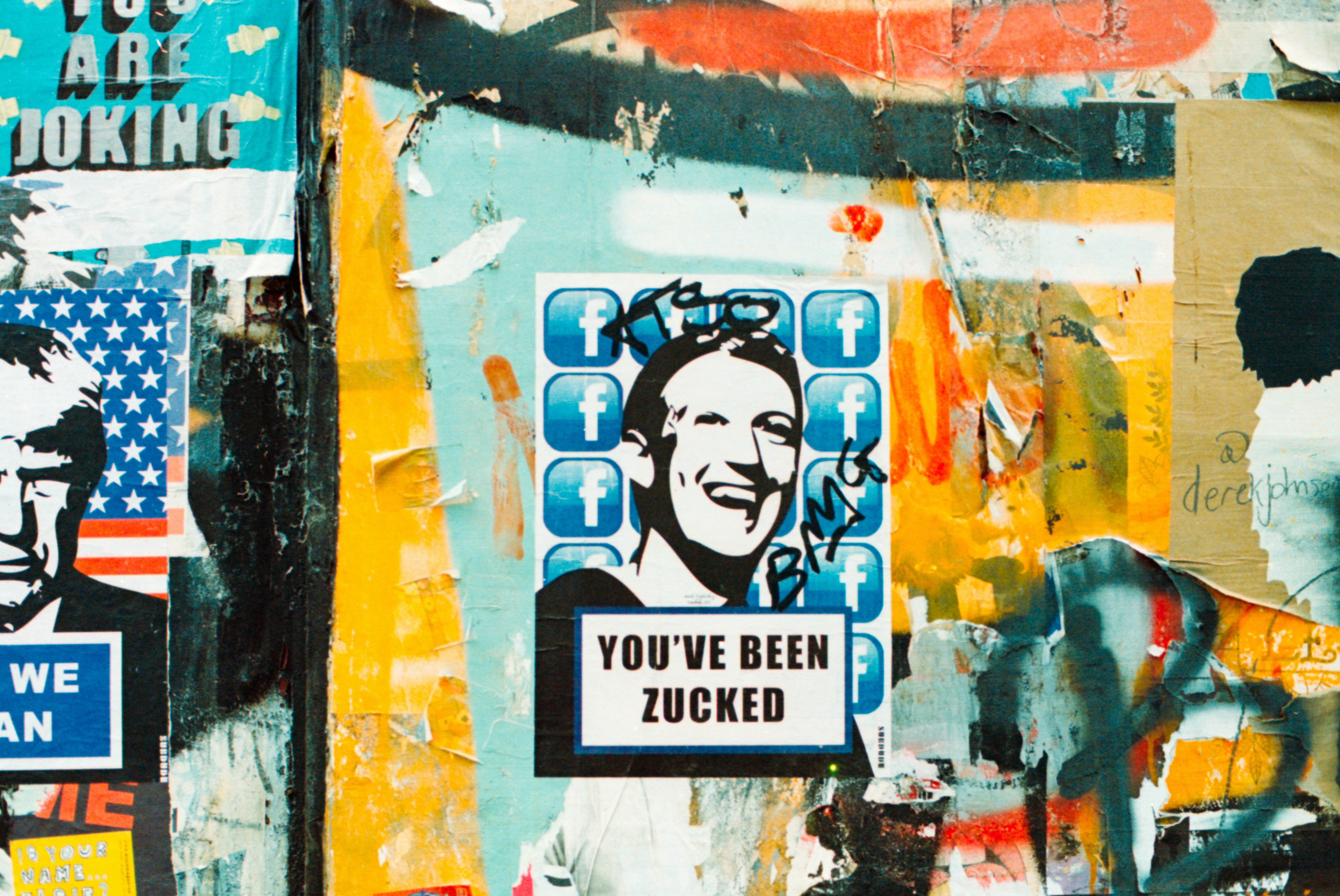 Graffiti collage with "YOU'VE BEEN ZUCKED" poster on colorful wall.