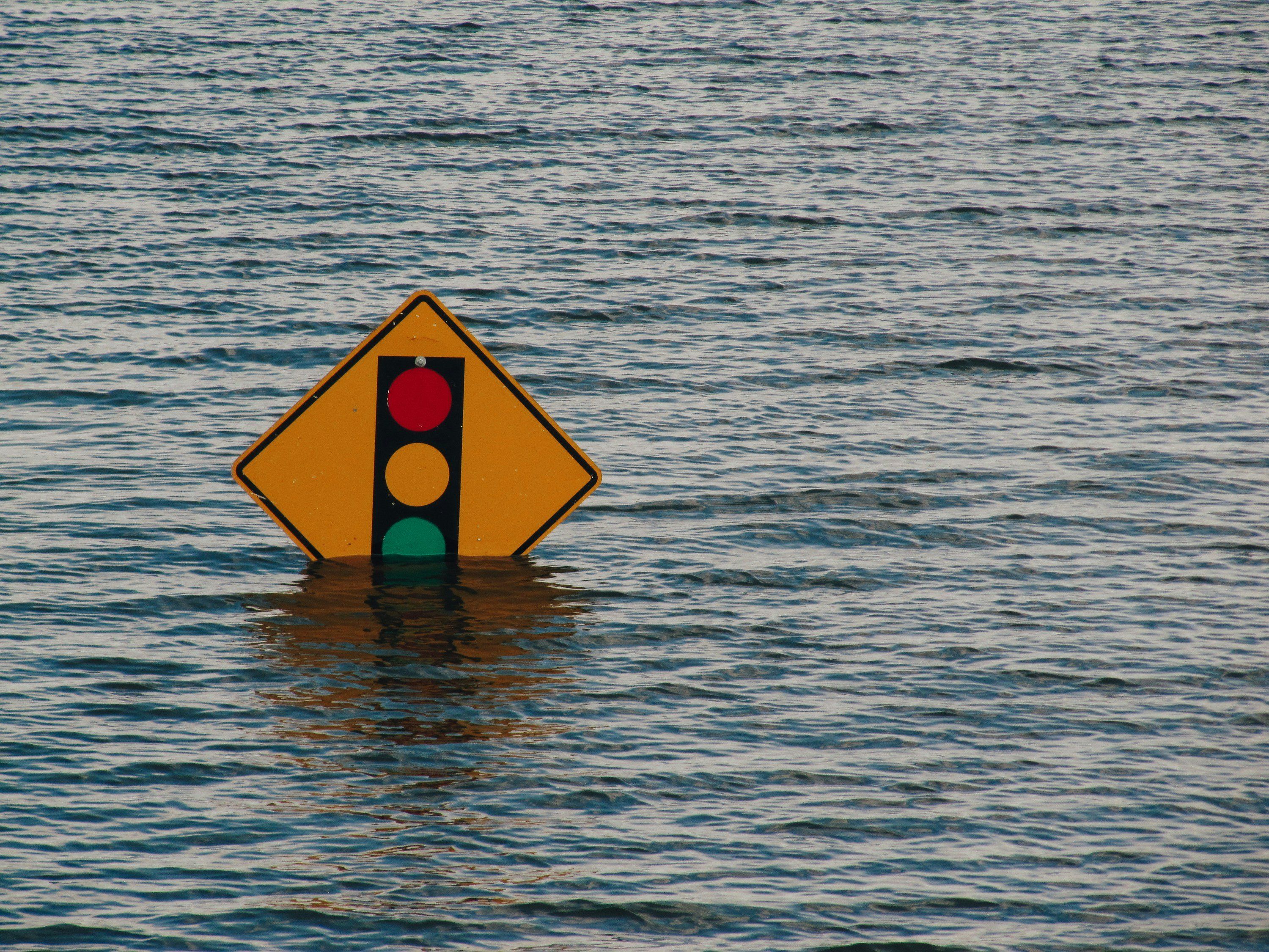 Traffic light sign partially submerged in water.