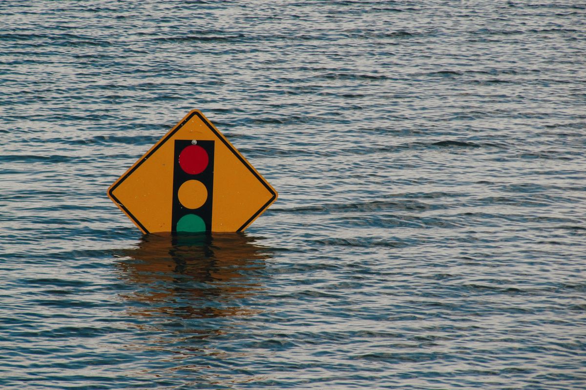 Traffic light sign partially submerged in water.