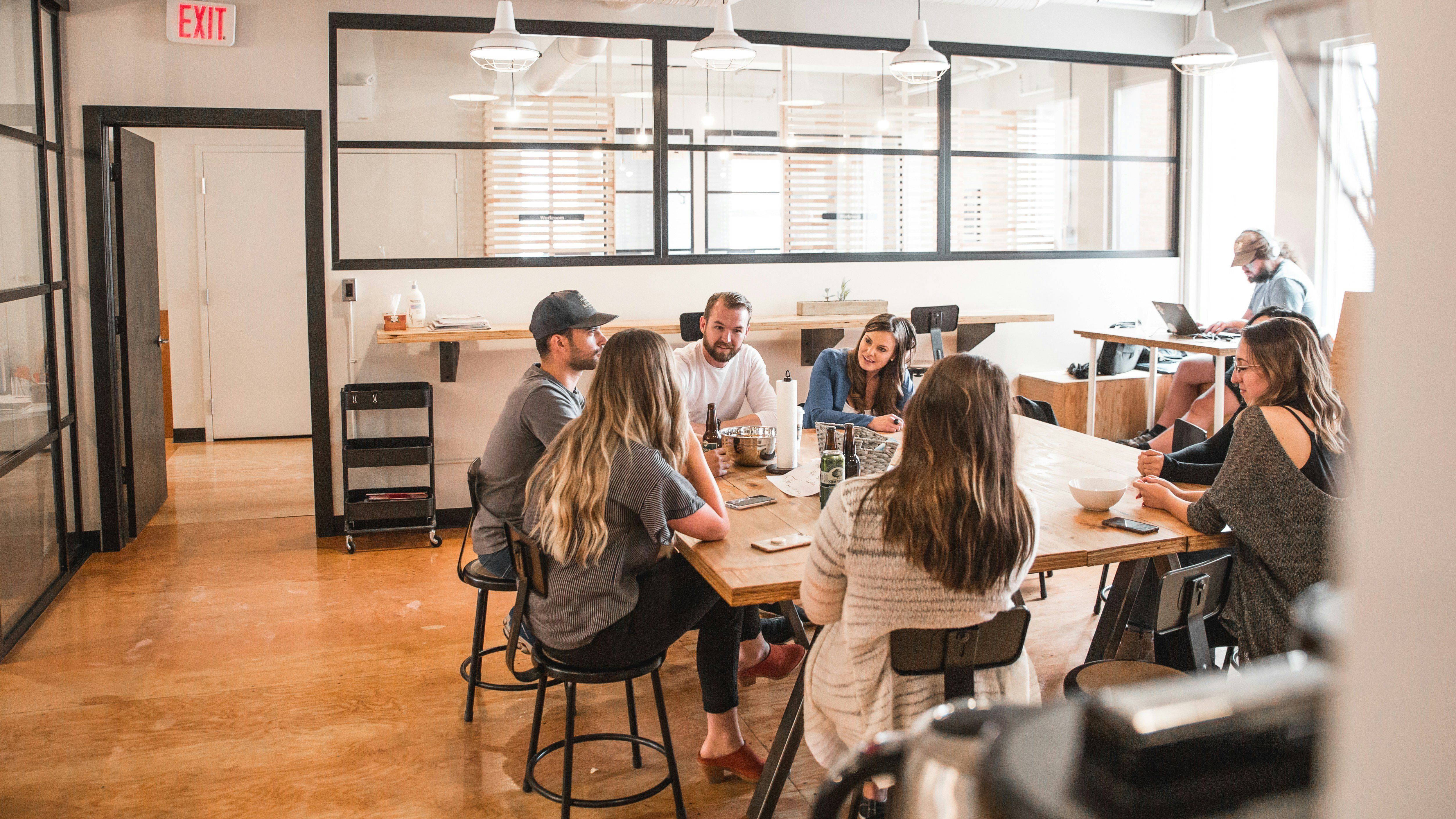 Colleagues having a meeting around a wooden table in a modern office setting.