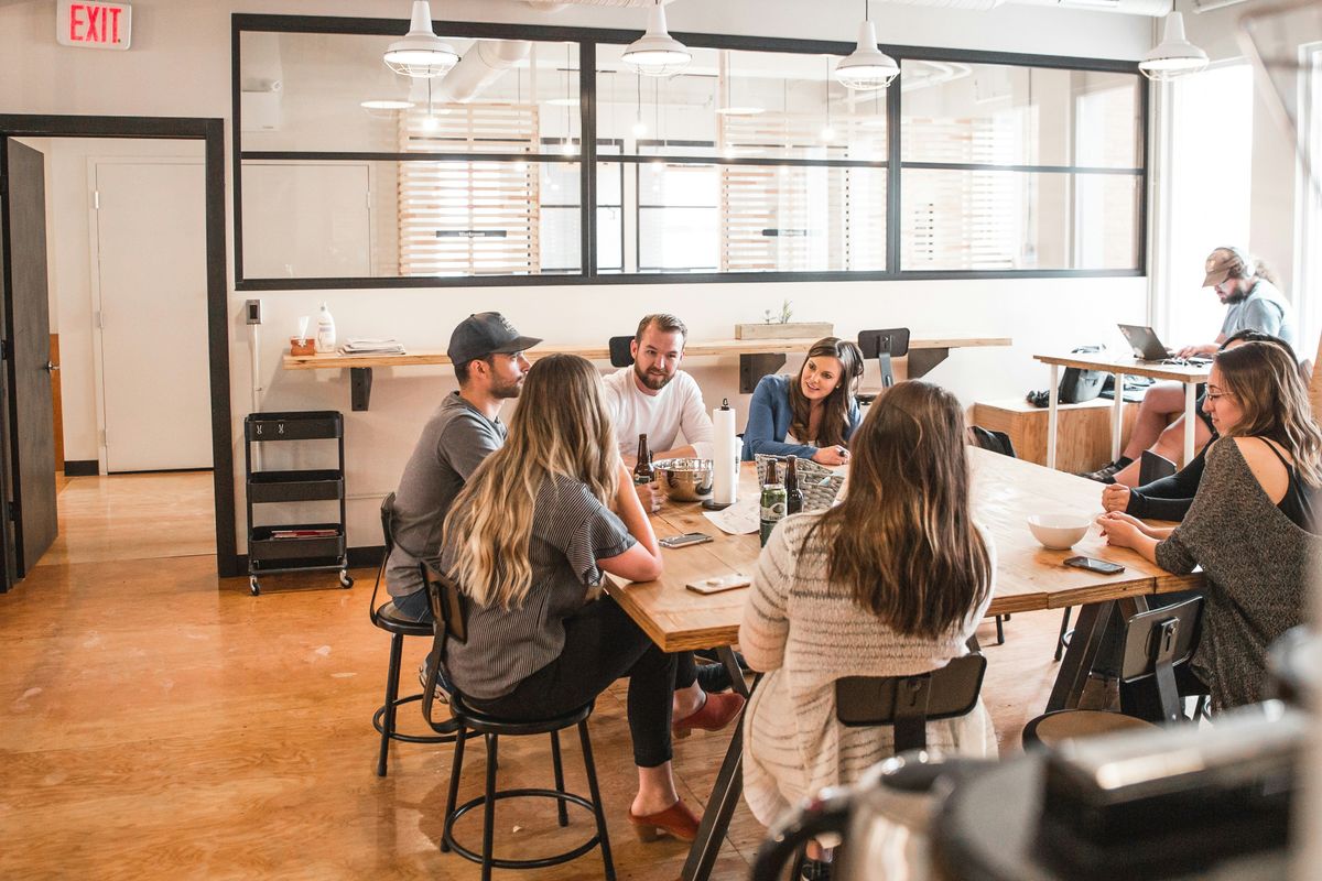 Colleagues having a meeting around a wooden table in a modern office setting.