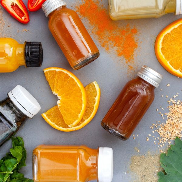 Juice shots for a healthy lifestyle, flat lay on dark grey with ingredients