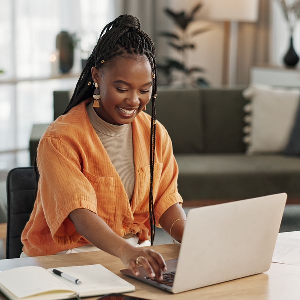 Black woman, typing in home office and laptop for research in remote work, social media or blog in apartment. Freelance girl at desk with computer writing email, website post and online chat in house